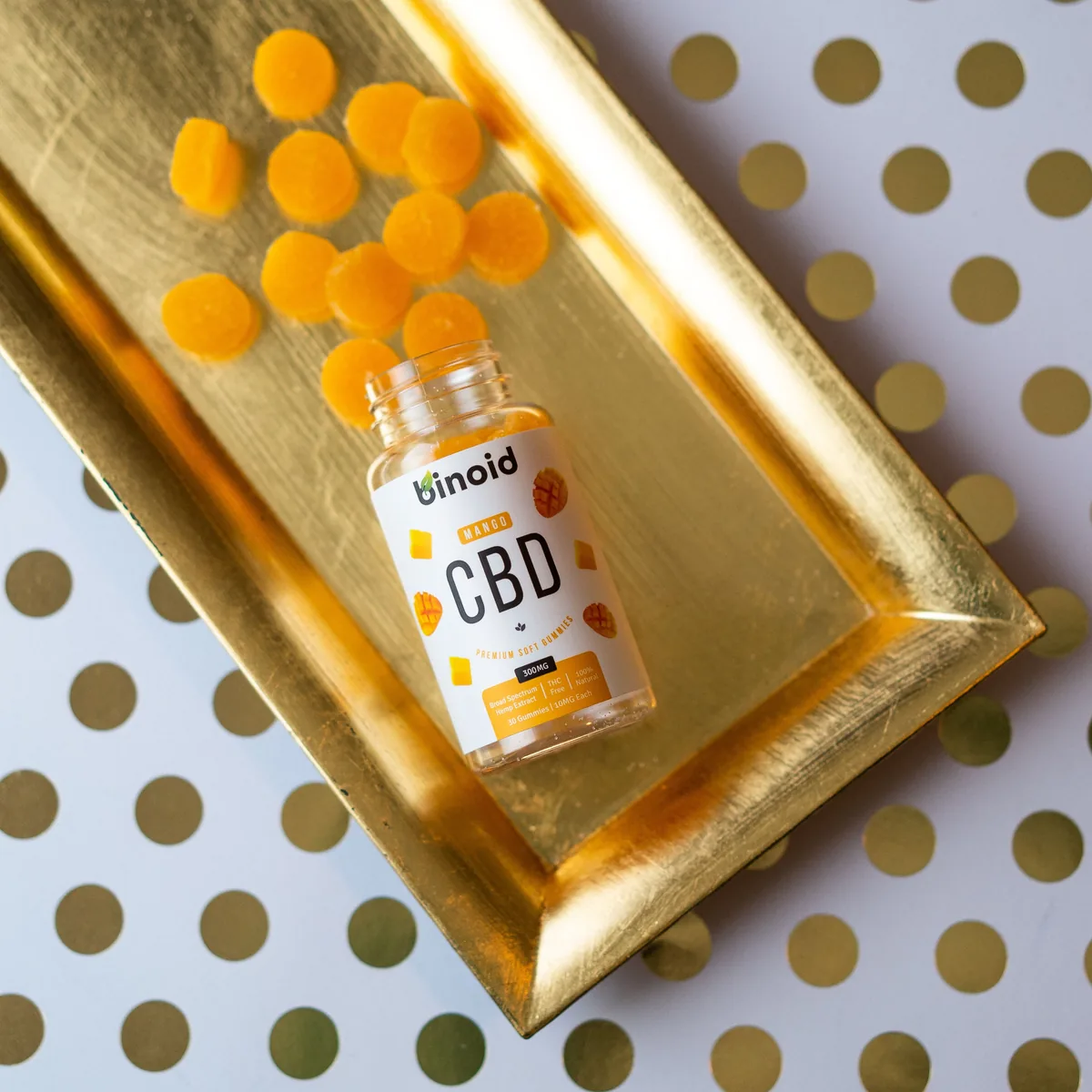 Mango broad-spectrum CBD gummies on a gold tray